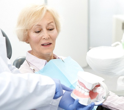 An older female patient listening as her dentist discusses her eligibility for implant dentures in Bethel Park