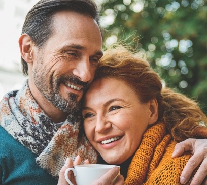 Man and woman smiling after dental implant tooth replacement