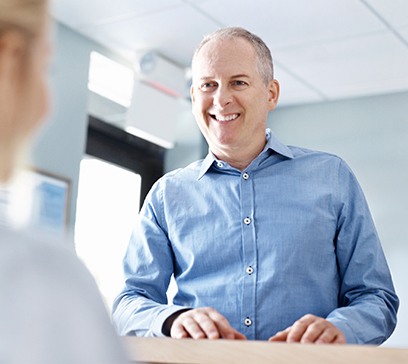 Man checking in at dental office reception desk