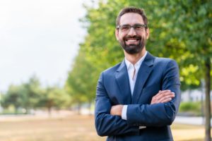 Confident businessman with dental implants smiles at work